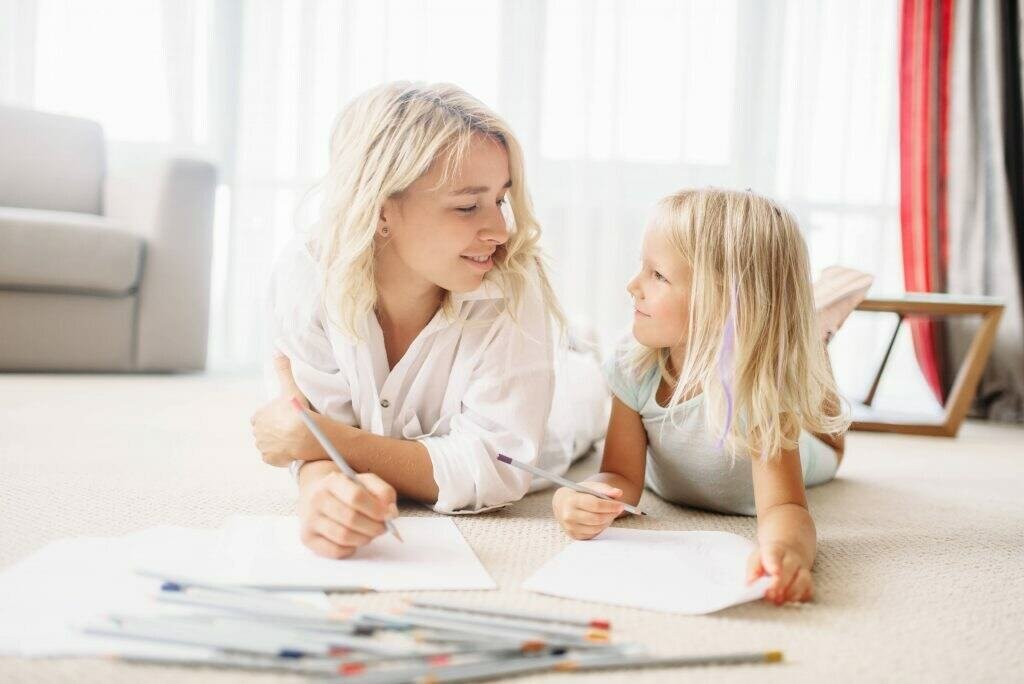 Mother and daughter lying on the floor and drawing