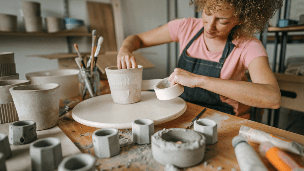 Female potter crafting different pots and other clay products