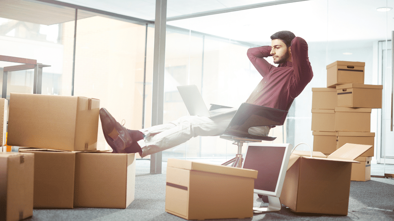 Man lounging on his char with a laptop on his lap and arms around his head, looking satisfied