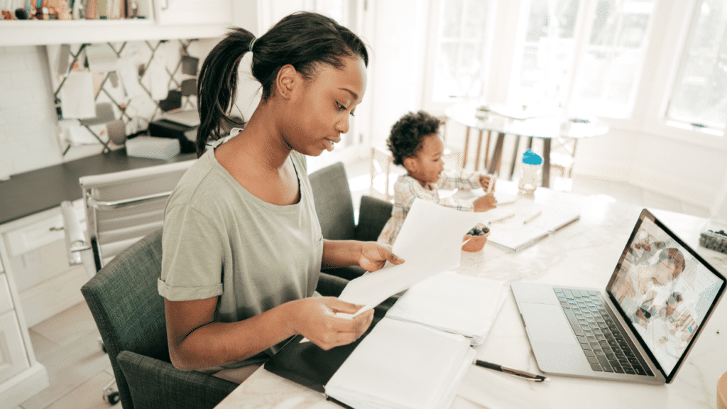 Mother working at home while spending time with her child