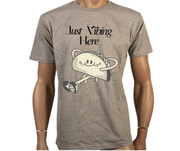 Funny Taco T-Shirt featuring a smiling taco character and "Just Vibing Here" text. Made from 100% combed cotton, lightweight and breathable for casual wear.